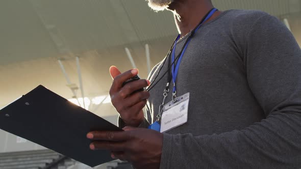 Midsection of african american male coach time cheking and making notes alt