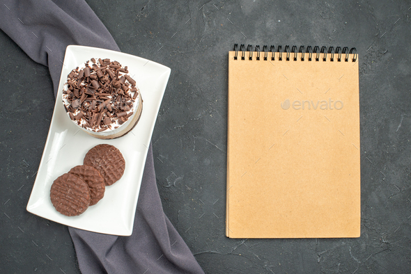 top view chocolate cake and biscuits on white rectangular plate purple shawl a notebook on dark