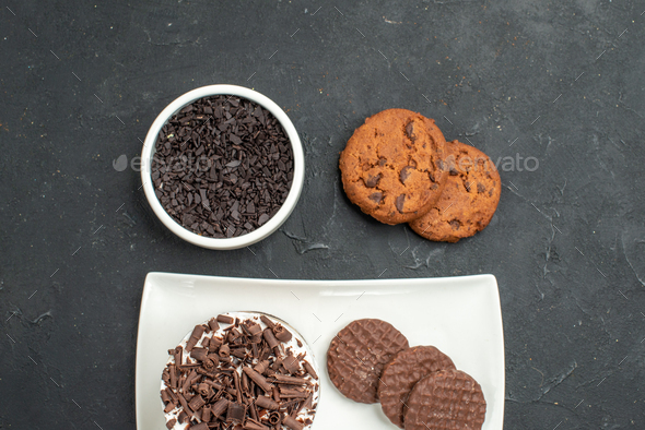 top view chocolate cake and biscuits on white rectangular plate bowl with chocolate biscuits on dark