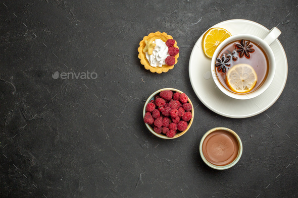 Overhead view of a cup of black tea with lemon served with chocolate raspberry honey on dark
