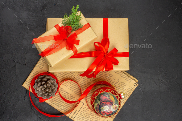 top view xmas gift in brown paper ribbon xmas tree toy on newspaper on dark background