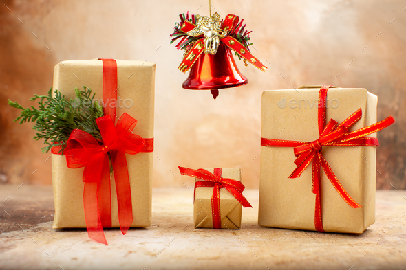 bottom view xmas gifts in brown paper ribbon xmas tree toys on newspaper on beige background