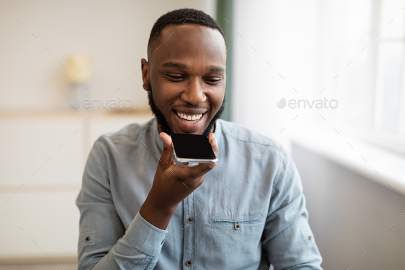 African Man Using Voice Search Holding Smartphone Near Mouth Indoor