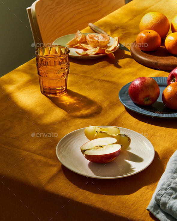 Food, breakfast with fruit. Table covering bright yellow linen tablecloth, sunlight deep hard shadow - Stock Photo - Images
