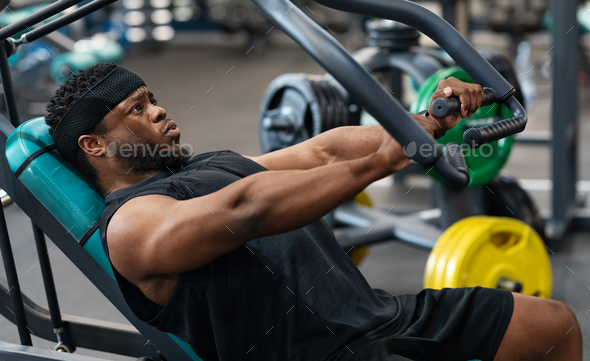 Athletic black man having workout on chest press machine