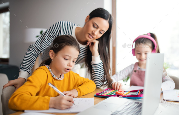 Mother with school girls indoors at home, distance learning and home office.
