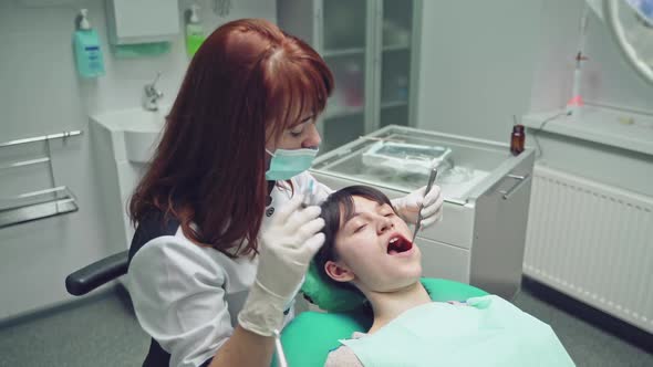 Female dentist in dental office talking with female patient and preparing for treatment. alt