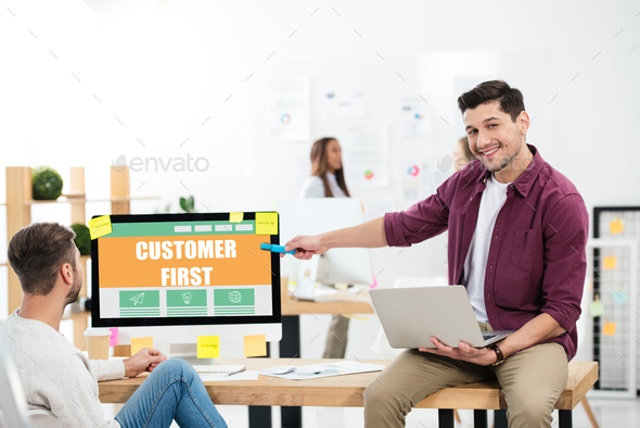 businessman pointing at customer first inscription on computer screen while working at workplace