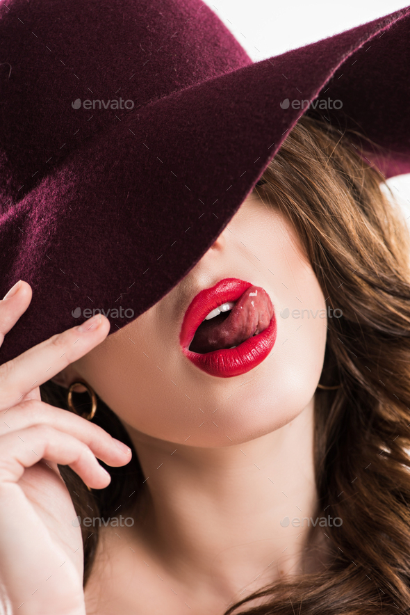 sexy woman sticking tongue out and hiding eyes under burgundy hat
