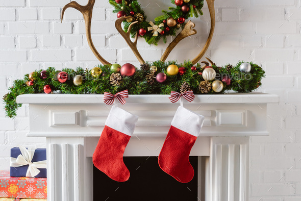 christmas wreath with decorations, stockings and deer horns over fireplace mantel
