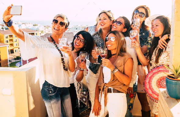 Group of people women enjoying party on the terrace celebrating and toasting with red wineglass - Stock Photo - Images