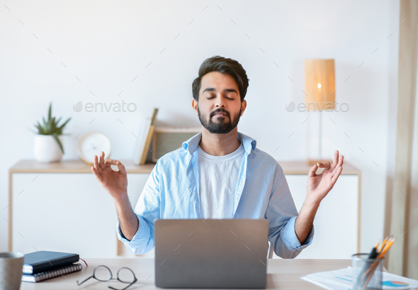 Working Zen. Calm Eastern Businessman Meditating At Workplace In Office