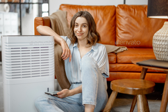 Woman sitting near air purifier and moisturizer appliance