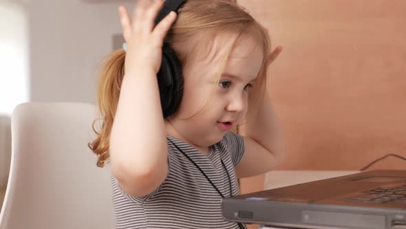 Child Listens to Music in Headphones Dances Rejoices and Smiles