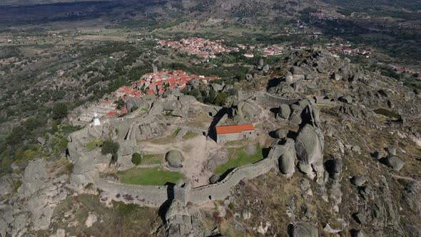 Drone camera captures a close up view of the boulders and rocks surrounding Monsanto Castle. alt