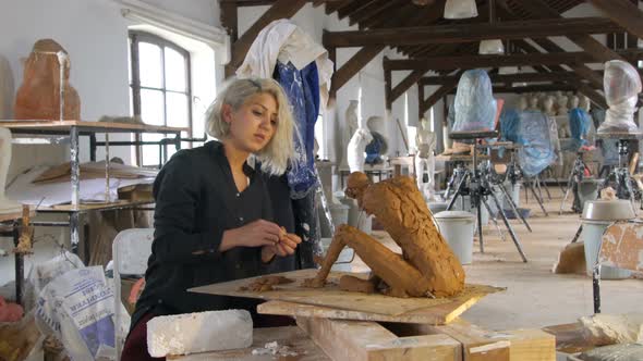 Sculptor is Sculpting a Realistic, Figurative Model in Large Studio