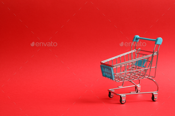 Blank shop trolley on red background, space for text