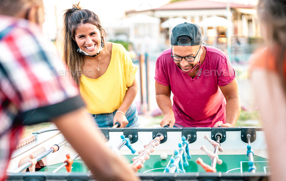 Multiracial friends play kicker table football at open space bar - Stock Photo - Images