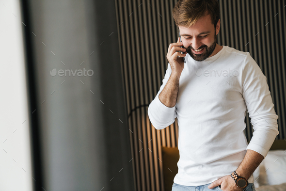 Attractive smiling young man using mobile phone