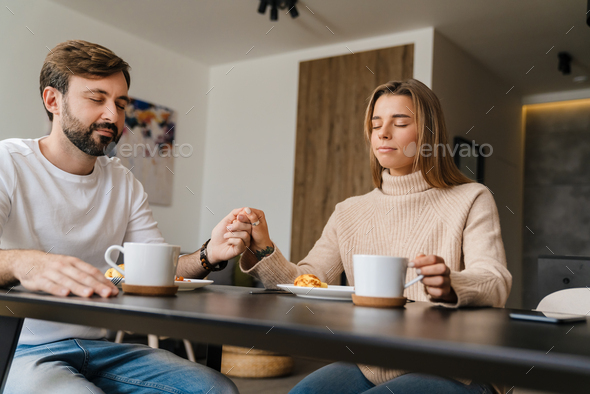 Couple praying while sitting at the dining table
