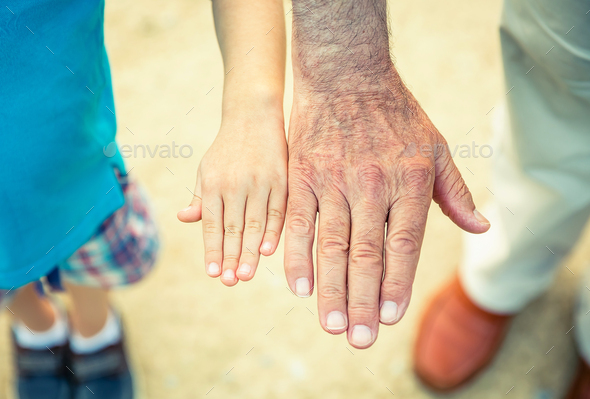 Child and senior man comparing his hands size