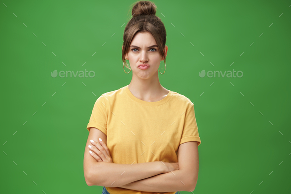 Girl not liking result of work looking displeased and serious at camera, frowning crossing hands