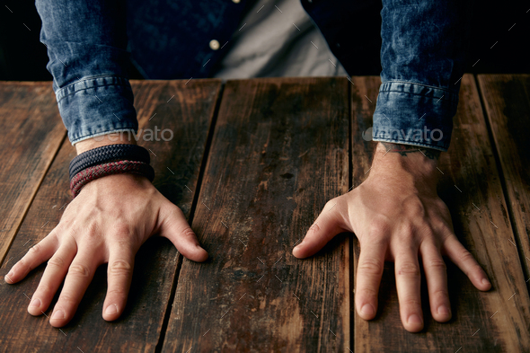 Beautiful men hands on table, jeans casual shirt, tattoo, wrist band, braceletes