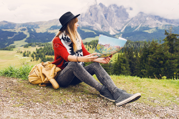 Traveler young woman with backpack and hat sitting on grass