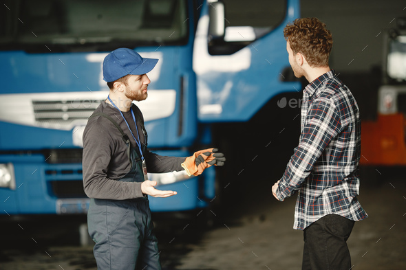 Two young men discuss work issues in garage
