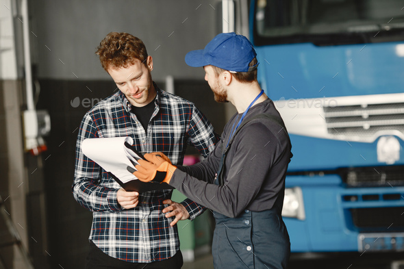 Two young men discuss work issues in garage