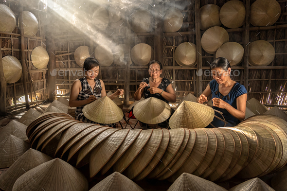Group of Vietnamese female craftsman making the traditional vietnam hat - Stock Photo - Images