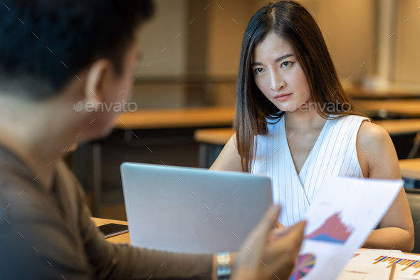 Rear view of Furious boss scolding Asian young businesswoman in casual suit