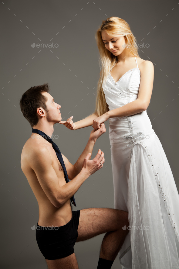 Young woman in wedding dress standing and touching man in