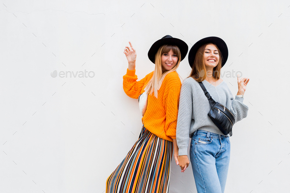 Bright stylish lifestyle urban portrait of two pretty best friends girls  posing at leather summer clothes,bright swag hats and sunglasses.Having  fun,send you kiss and say hello.summer swag girls style - Stock Image -