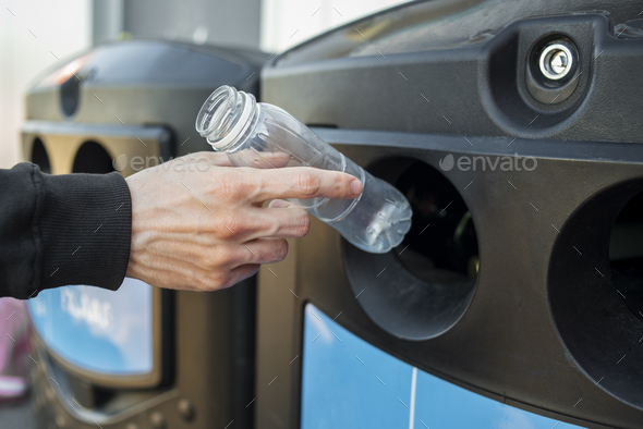 Man hand throwing plastic bottle into recycling bin