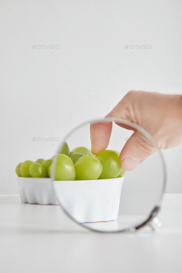 Magnified hand takes one grape - Stock Photo - Images
