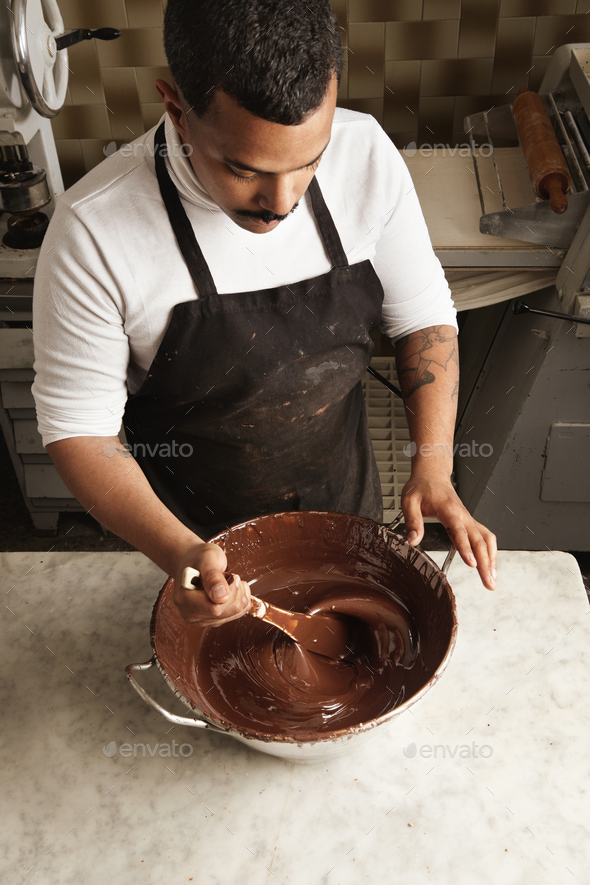 Professional chief black man twist tasty melted chocolate in big steel pot