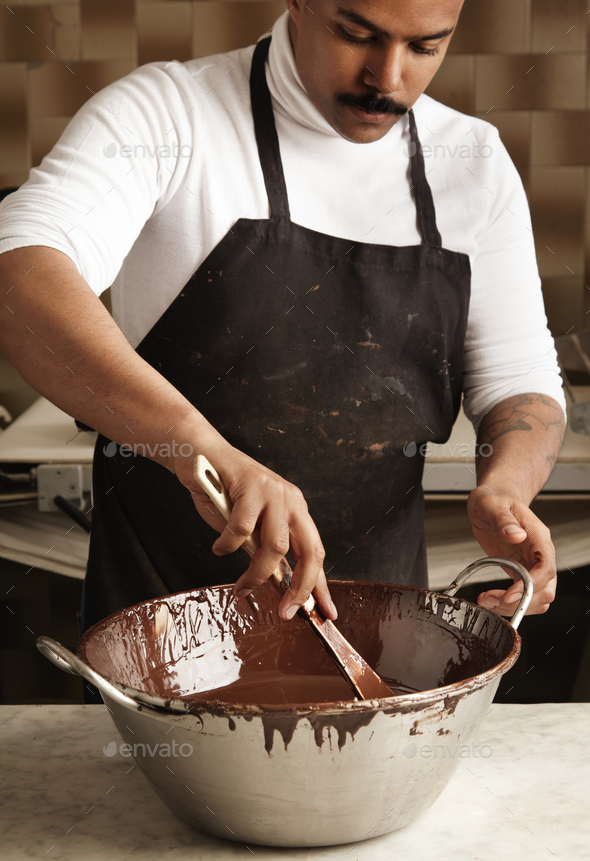 Professional chief black man twist tasty melted chocolate in big steel pot