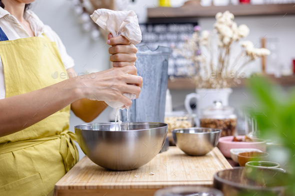 Woman pouring almond milk in bowl to squeeze out almond milk. Stock ...