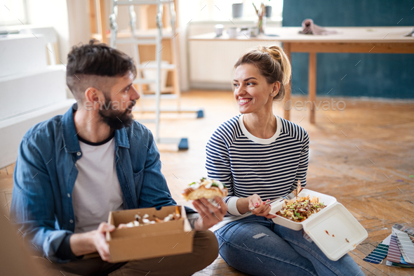 Couple eating lunch indoors at home, relocation, diy and food delivery concept