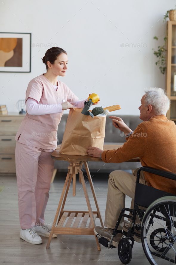Young Nurse Bringing Groceries to Senior Man