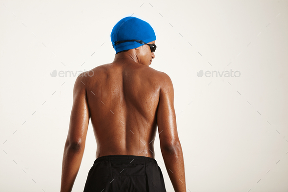 Back of a strong black swimmer in cap and goggles
