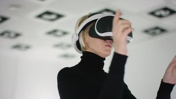 Close Up Shot of a Young Woman in a Virtual Reality Headset Standing and Making Hand Gestures in a