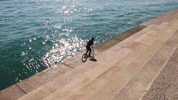 Bikers goes with a fixie near the water in Barcelona alt