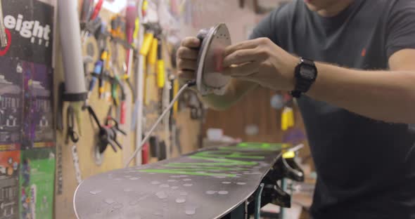 Repairman Doing Waxing And Ironing. Snowboard Maintenance And Repair Concept. alt