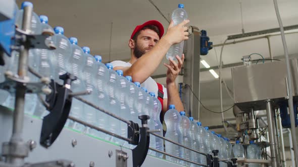 Young Man Worker of Water Factory Checking Quality and Making Inspection in Line Production