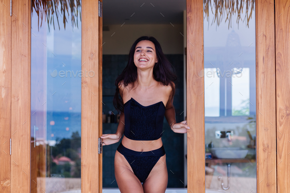 Caucasian fit tanned woman wearing vintage old bikini, posing at luxury hotel villa