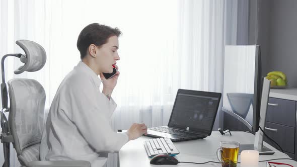 Female Entrepreneur Talking on Her Phone While Working on Two Computers alt