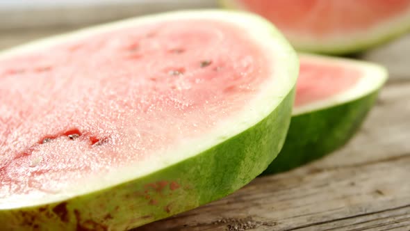 Slices and halved of watermelon on wooden table alt