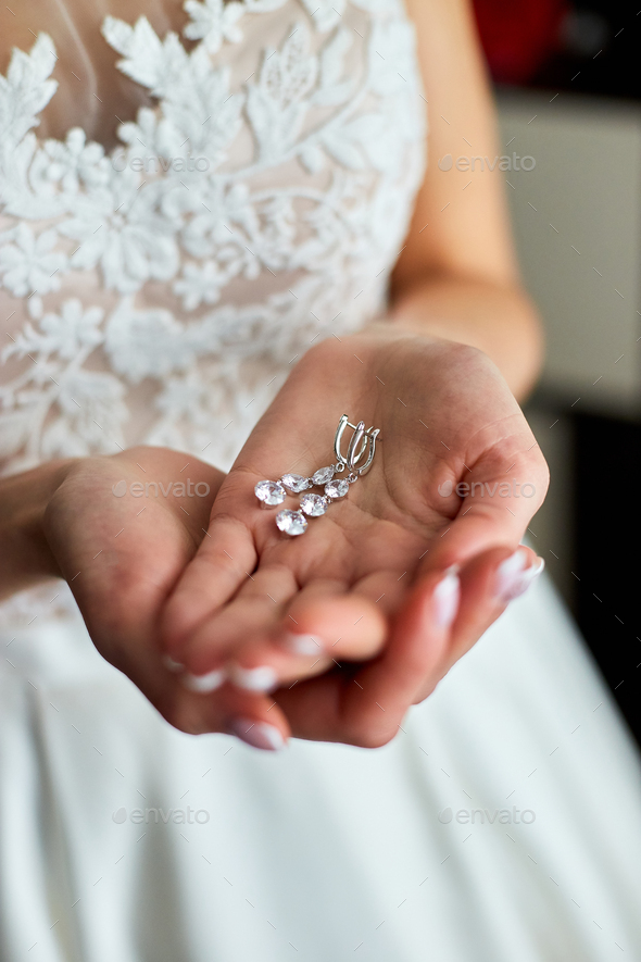 Wedding earrings on a female hand, she takes the earrings, the bride fees, - Stock Photo - Images